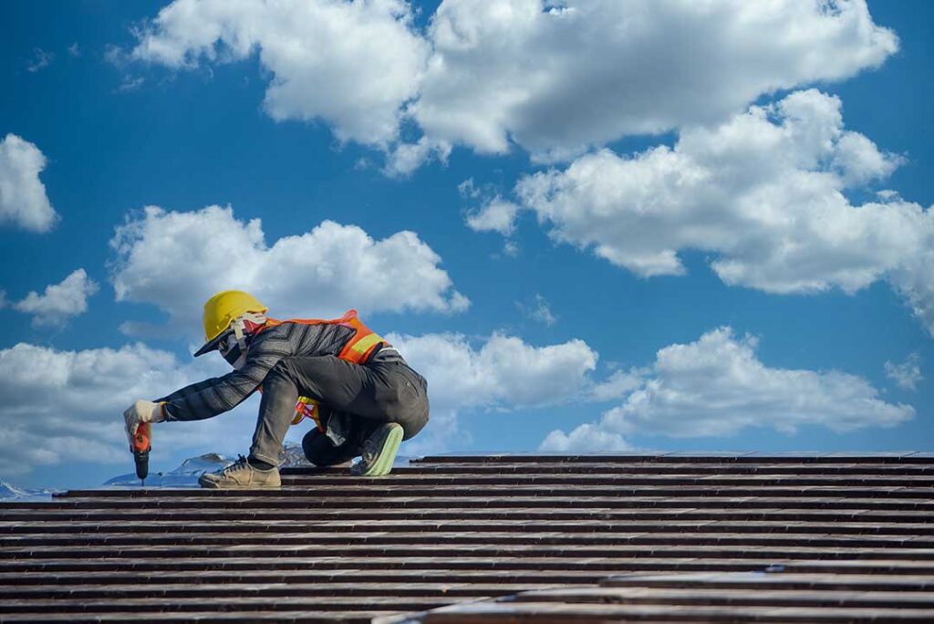 Homeowner inspecting gutters and roof edges from the ground before a snowy winter storm